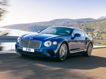De nieuwe Bentley Continental GT, met hout verwerkte details, rijdt op een bergweg.