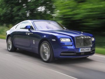 De blauwe Rolls Royce, een van de top 10 automerken met de hoogste CO2-uitstoot in Europa, rijdt over de weg.