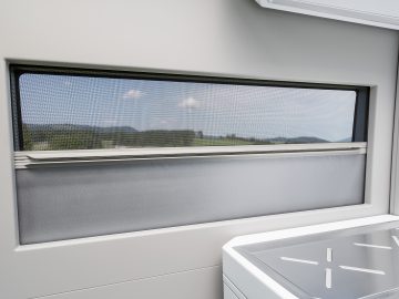 Een raam met uitzicht op een keuken in een trein, voorgesteld als een natte droom voor iedere Nederlandse kampeerder.
