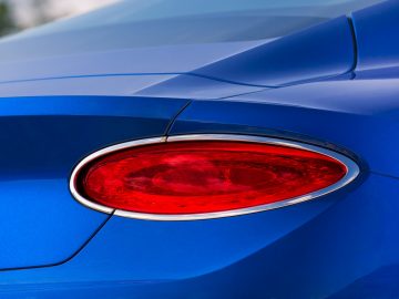 Een blauwe Bentley Continental GT met een rood achterlicht.