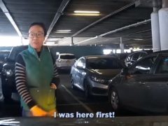 Een vrouw staat op een parkeerplaats.