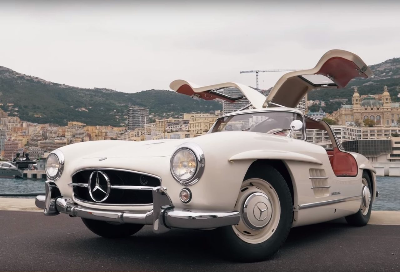 Een video van een Mercedes-Benz 300SL Gullwing uit 1955 geparkeerd voor een gebouw.
