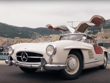 Een video van een Mercedes-Benz 300SL Gullwing uit 1955 geparkeerd voor een gebouw.