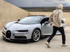 Een man in een hoodie staat naast een Bugatti Veyron, die doet denken aan de rijstijl van de auto.