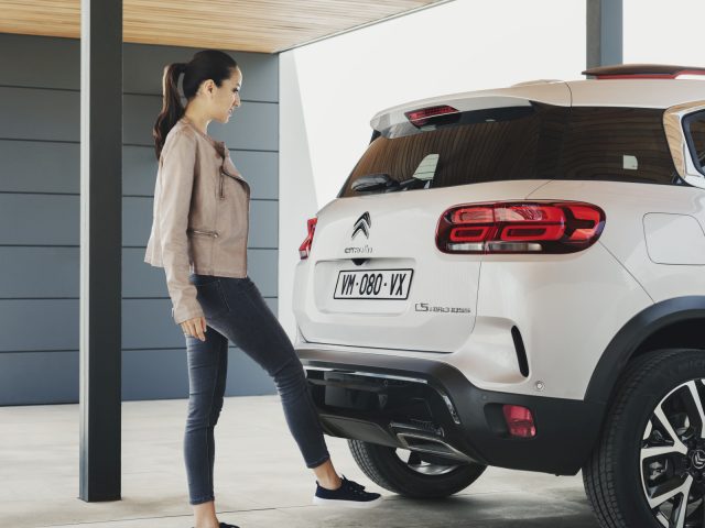 Een vrouw staat naast een witte Citroën C5 Aircross SUV.
