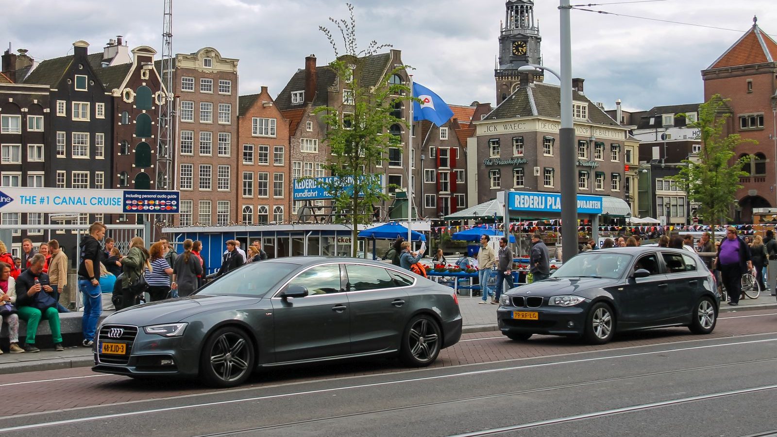 Een grijze Audi geparkeerd voor een gebouw met een tolheffingsbord in Amsterdam.