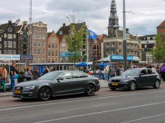 Een grijze Audi geparkeerd voor een gebouw met een tolheffingsbord in Amsterdam.