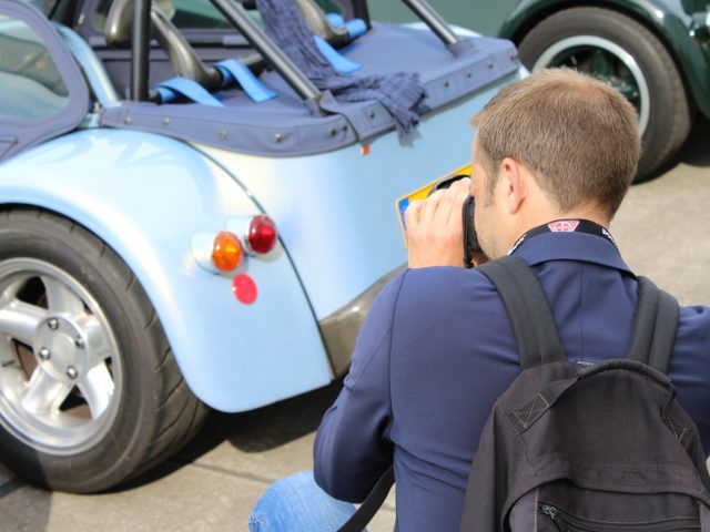 Een man die een foto maakt van een blauwe Donkervoort-sportwagen.