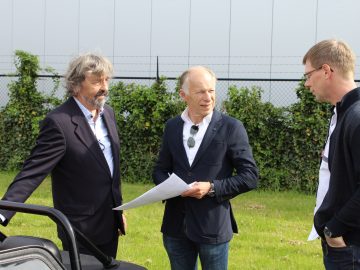 Drie mannen staan naast een Donkervoort-auto.