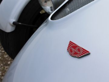 Een close-up van een Donkervoort-badge op een witte auto.