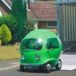 Een groene auto met eigenaardigheden geparkeerd voor een huis.