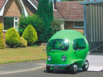 Een groene auto met eigenaardigheden geparkeerd voor een huis.