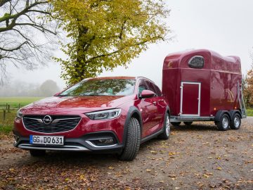 Een rode Opel Insignia met daaraan een paardentrailer.