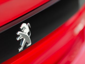 Een close-up van het Peugeot 508-logo op een rode auto.