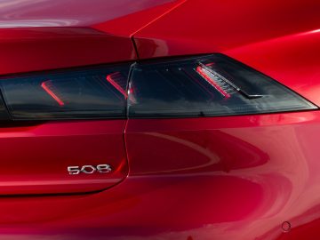 De achterlichten van een rode Peugeot 508.