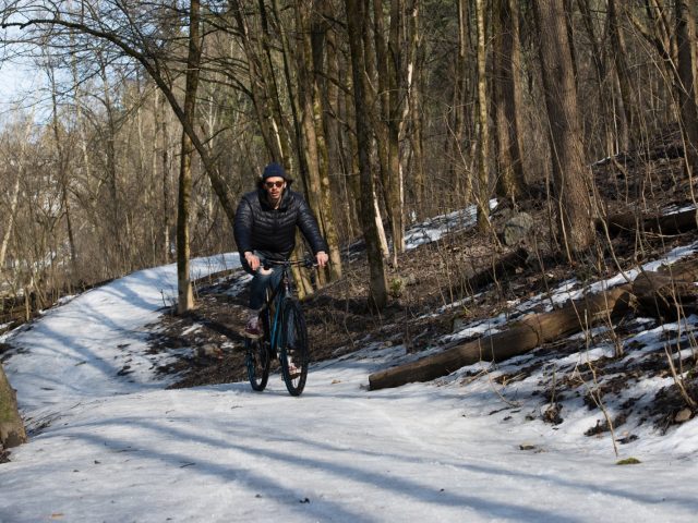 Een man rijdt op een fiets uitgerust met ReTyre-technologie over een besneeuwd pad.