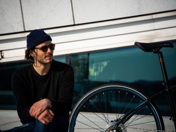 Een man zit op een bankje naast een ReTyre-fiets.