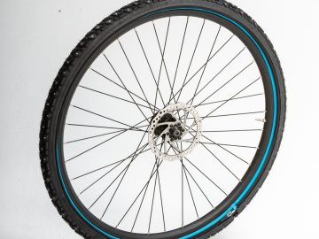 Een ReTyre-fietswiel met blauwe velgen tegen een witte achtergrond.
