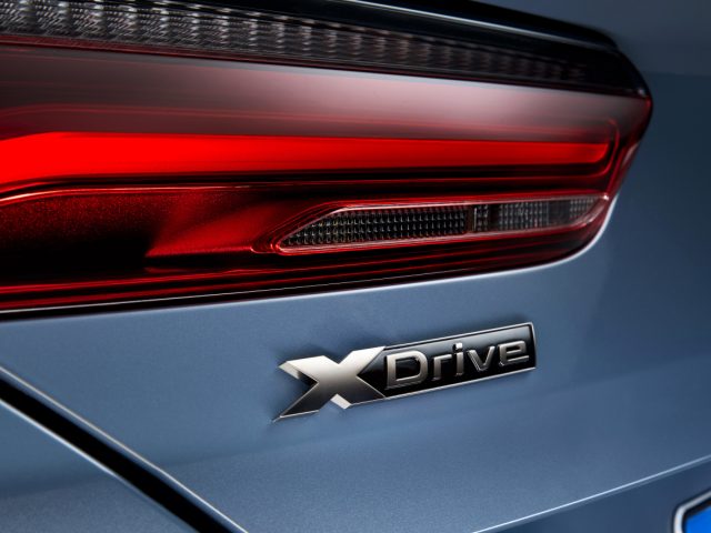De achterkant van een blauwe BMW 8 Serie Coupé met het x drive-logo.