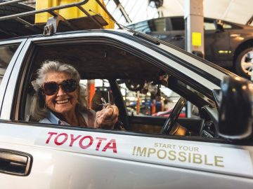 Een vrouw bestuurt een Toyota Corolla-auto bij een Toyota-dealer.