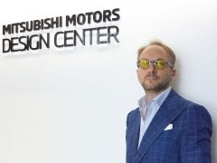 Een man in pak staat naast een bord met de tekst Mitsubishi Motors Design Center met Alessandro Dambrosio.