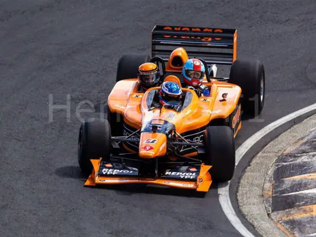 Een Arrows AX3 Formule 1-auto met drie zitplaatsen, in het oranje, racend over de baan.