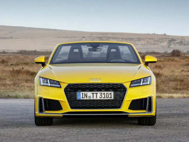 Een gele Audi TT op een woestijnweg.