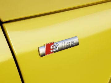 Een close-up van een gele Audi-badge op een auto.