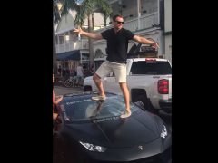 Een man staat bovenop een zwarte Lamborghini-sportwagen.