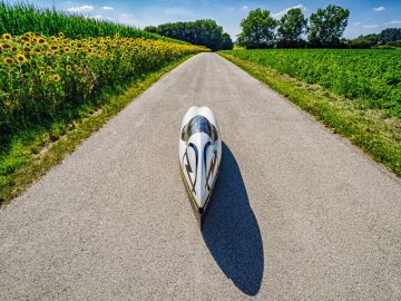 Een witte kano geparkeerd op een weg in een veld met zonnebloemen, gefotografeerd door Nicola Walde.