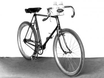 Een zwart-witfoto van een fiets met Nicola Walde Opel-waterflessen.