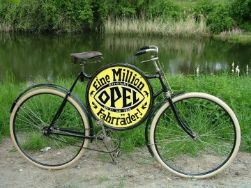Een Nicola Walde Opel-fiets met een bord erop naast een watermassa.