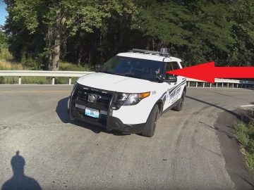 Een politieauto staat langs de kant van de weg geparkeerd na een bizar incident waarbij een fietser frontaal werd aangereden door een sms'ende politieagent.