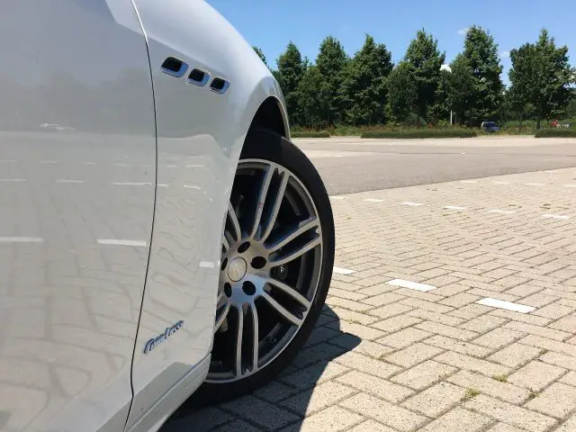 Op een parkeerplaats staat een witte Maserati Ghibli geparkeerd.