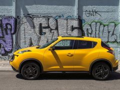 Een Nissan Juke geparkeerd voor een graffitimuur.