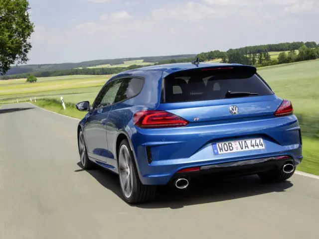 De achterkant van een blauwe Volkswagen Golf R die over een landweg rijdt.