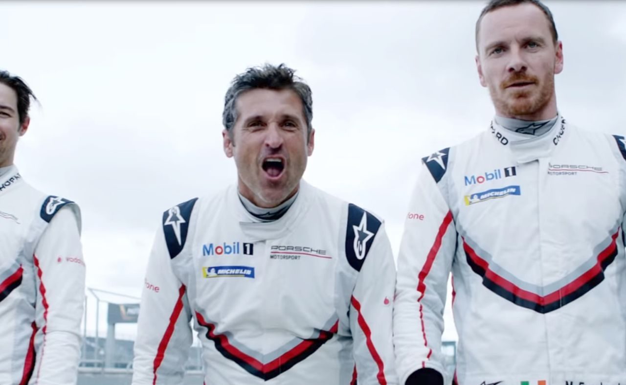 Drie mannen in racepakken staan naast elkaar, naast de Porsche 919 Hybrid.