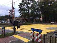 Een ProRail-treinovergang met gele verf aan de kant van de weg.