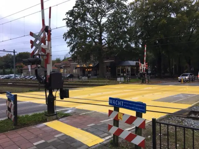 Een ProRail-treinovergang met gele verf aan de kant van de weg.