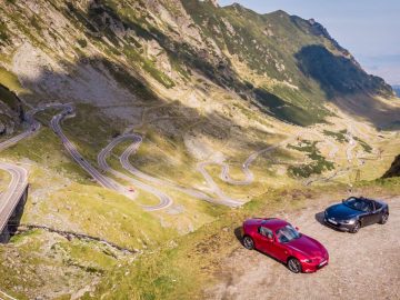Twee rode sportwagens rijden over de Transfagarasan-bergweg.