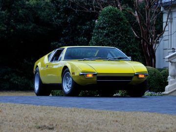 Een gele sportwagen van De Tomaso geparkeerd voor een huis.