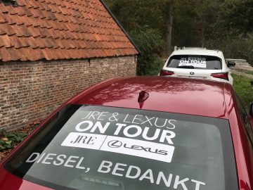 Een auto met een JRE-sticker op de voorruit.