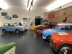 Een verzameling oude auto's, waaronder Trabants, in een museum.