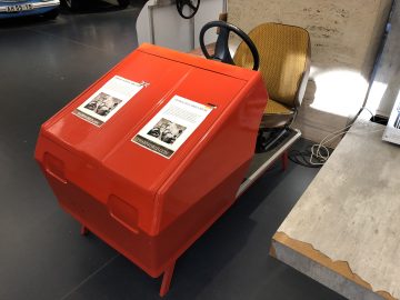 Een rode Trabant zittend op een tafel in een museum.