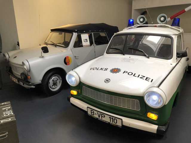Twee Trabant-politieauto's geparkeerd in een museum.