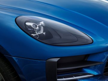 De koplamp van een blauwe Porsche Macan.
