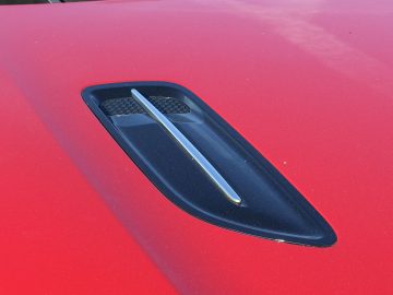 Een close-up van de motorkap van een rode Kia Stinger-sportwagen.