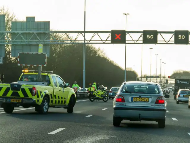 Een verkeerslicht met een kruiskruis aan de kant van de weg.