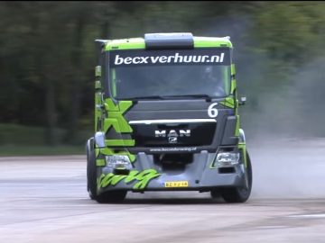 Een groene vrachtwagen rijdt over een onverharde weg.