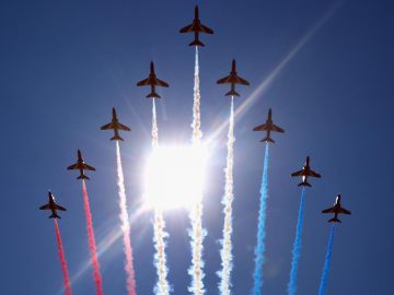 Een groep rode, witte en blauwe straaljagers vliegt in formatie boven Zandvoort.